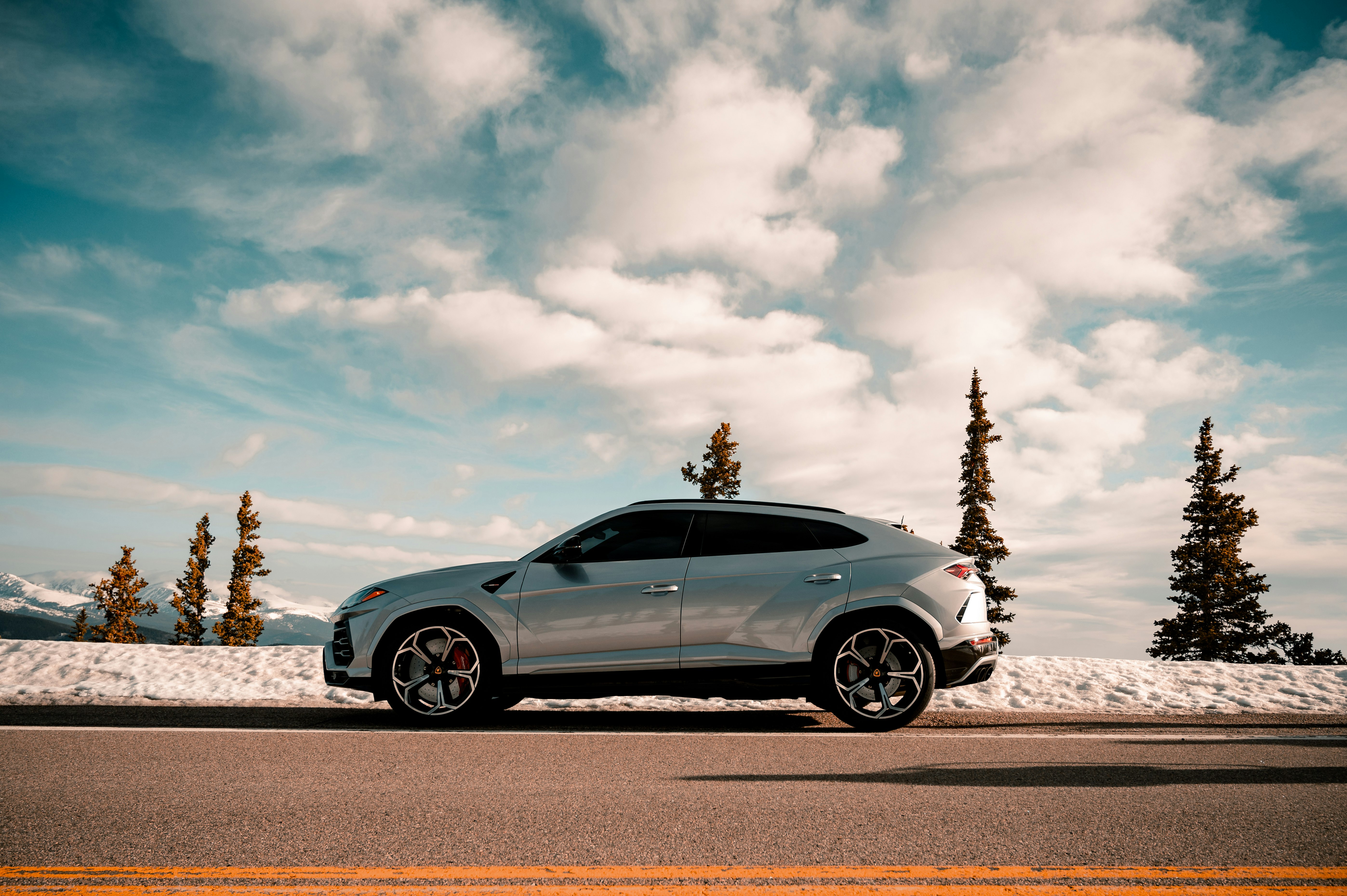 blue coupe on gray asphalt road under white clouds and blue sky during daytime